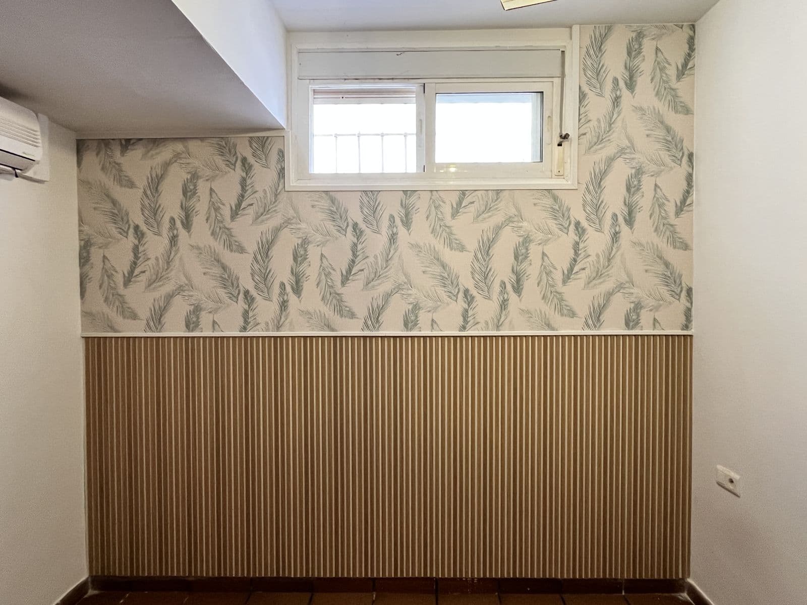 Pared con papel pintado de hojas y panelado de listones de madera