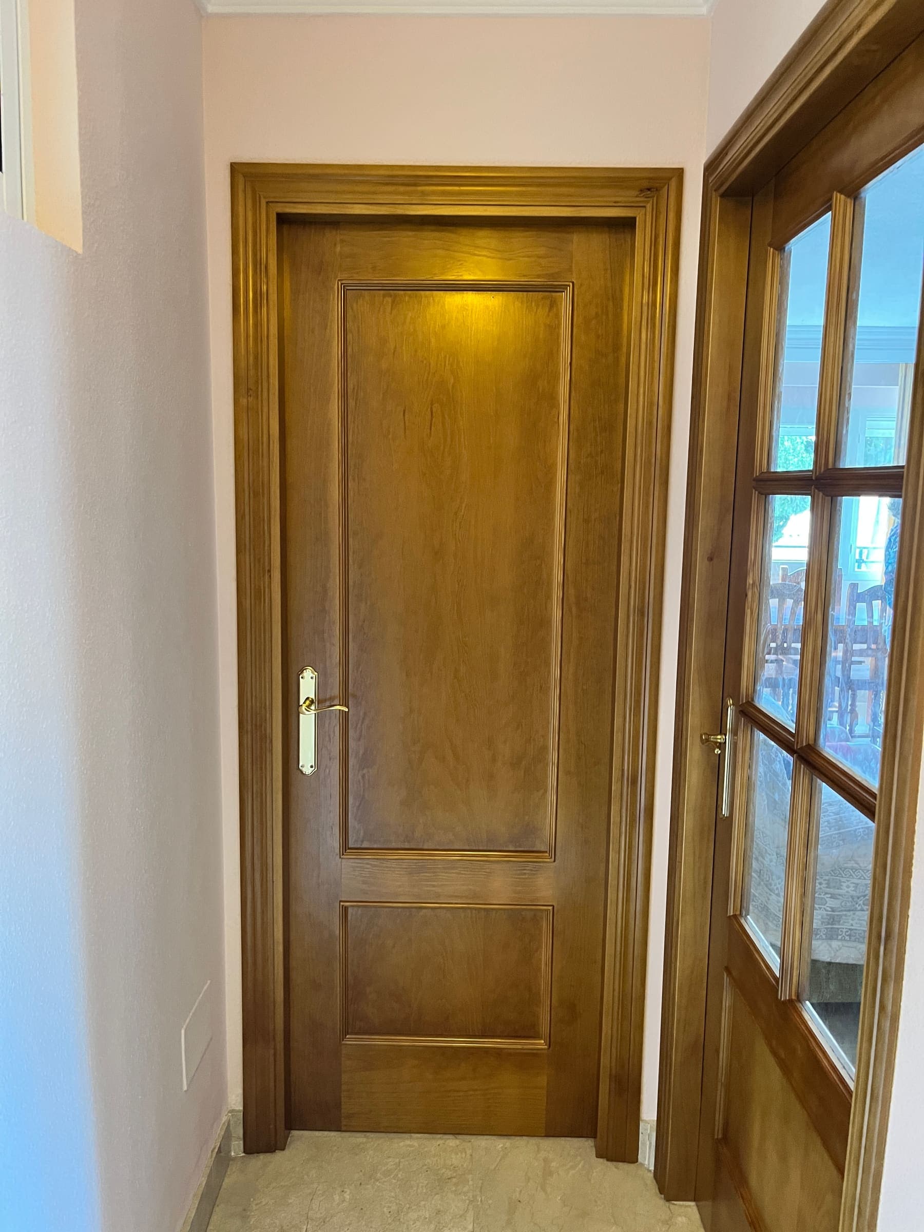 Puerta y tragaluz de madera a medida con acabado en tono nogal